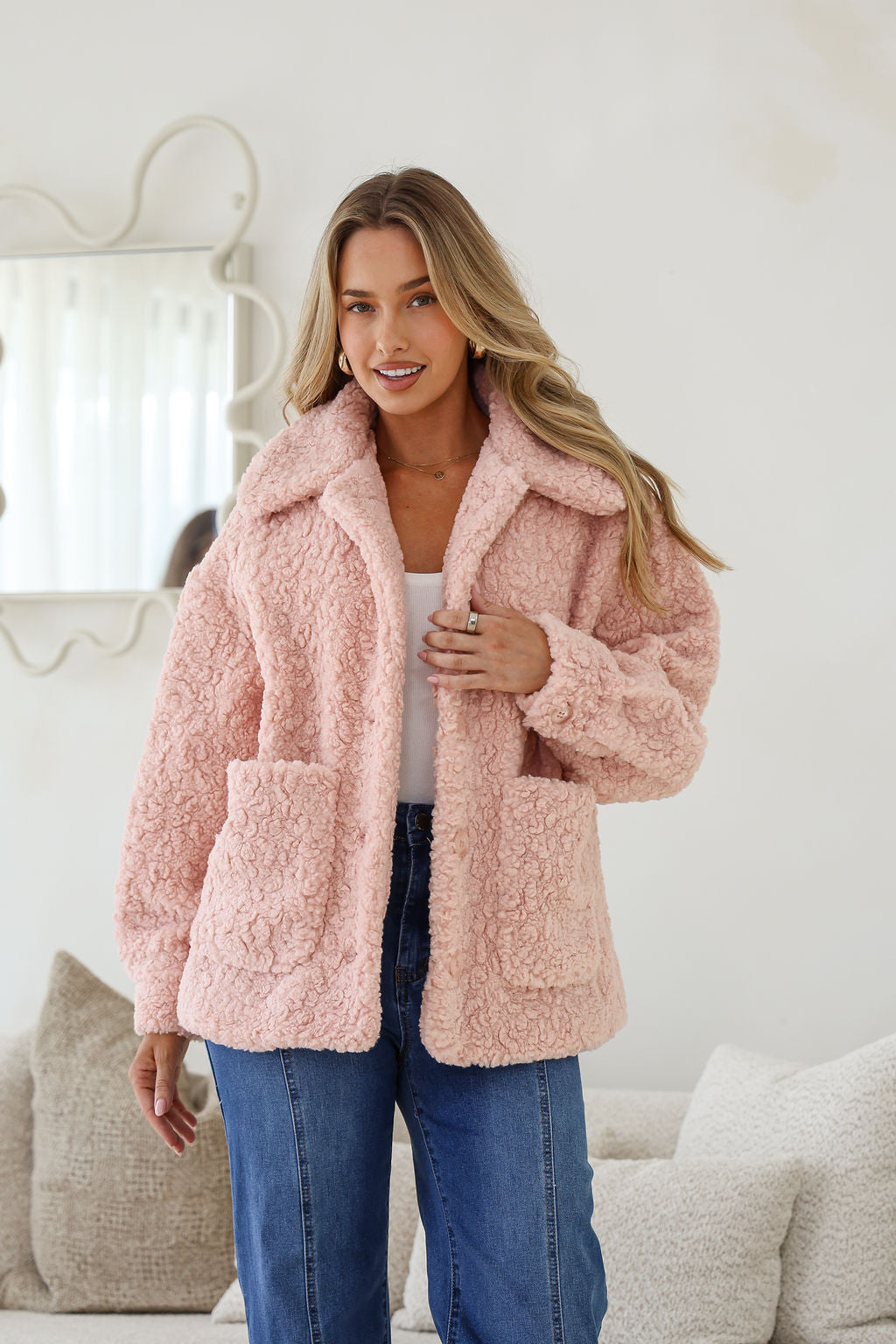 Woman wearing a pink fluffy coat in a cozy living room setting