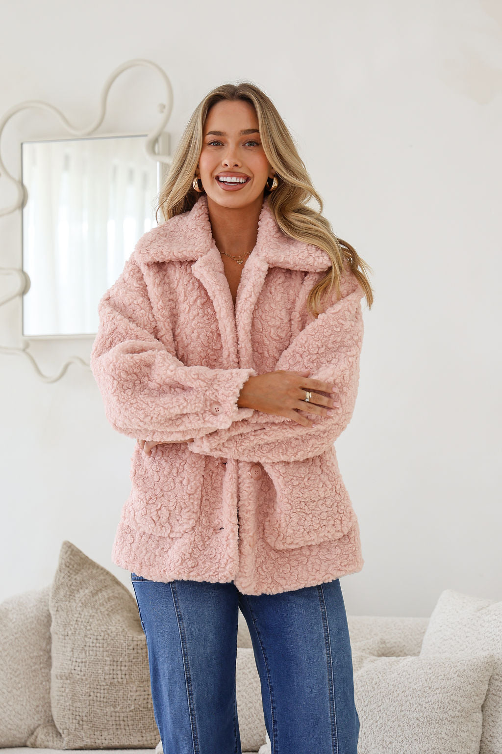 A woman smiling and wearing a pink teddy boucle jacket with an oversized collar, front patch pockets, and full button-through front.