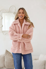 A woman smiling and wearing a pink teddy boucle jacket with an oversized collar, front patch pockets, and full button-through front.