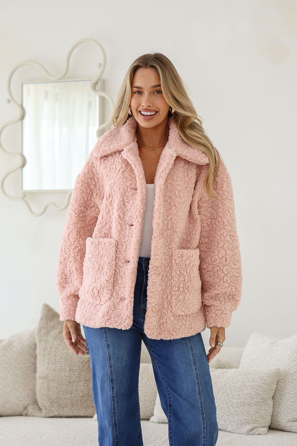 Woman wearing a pink sherpa jacket in a cozy living room setting