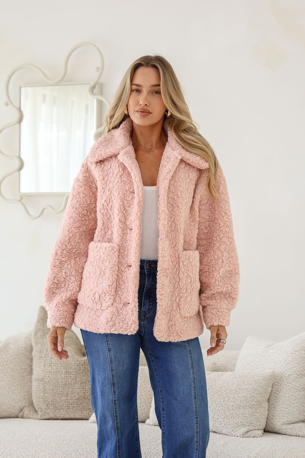 Woman wearing a pink fluffy jacket in a living room setting