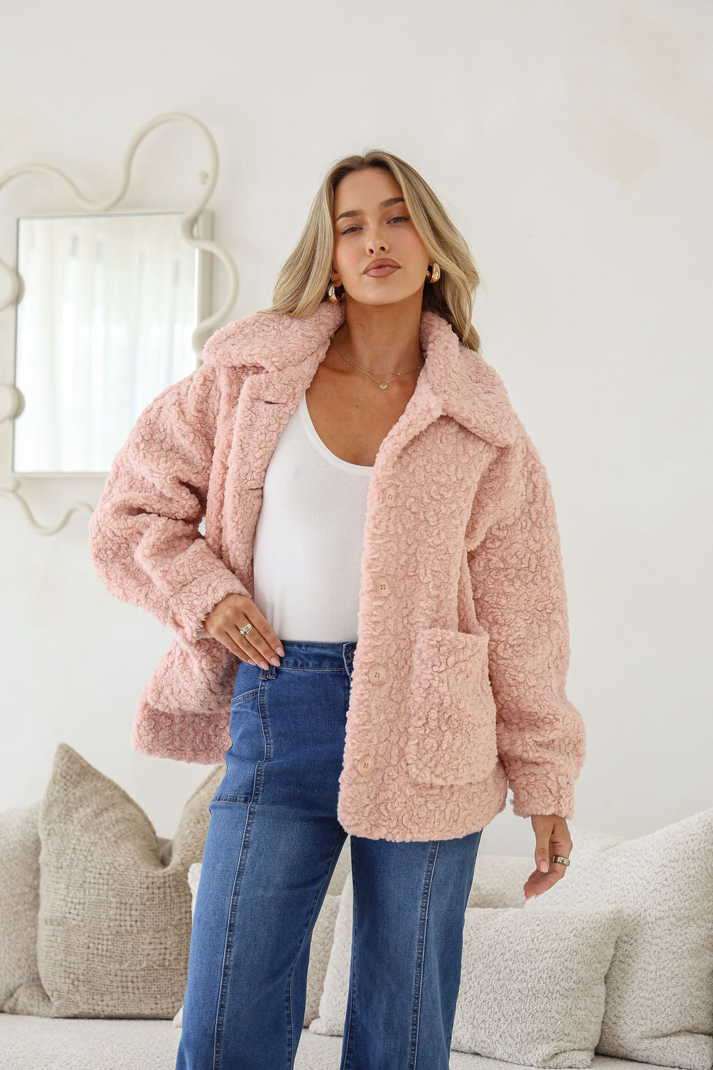 Woman wearing a pink fluffy jacket in a cozy living room setting