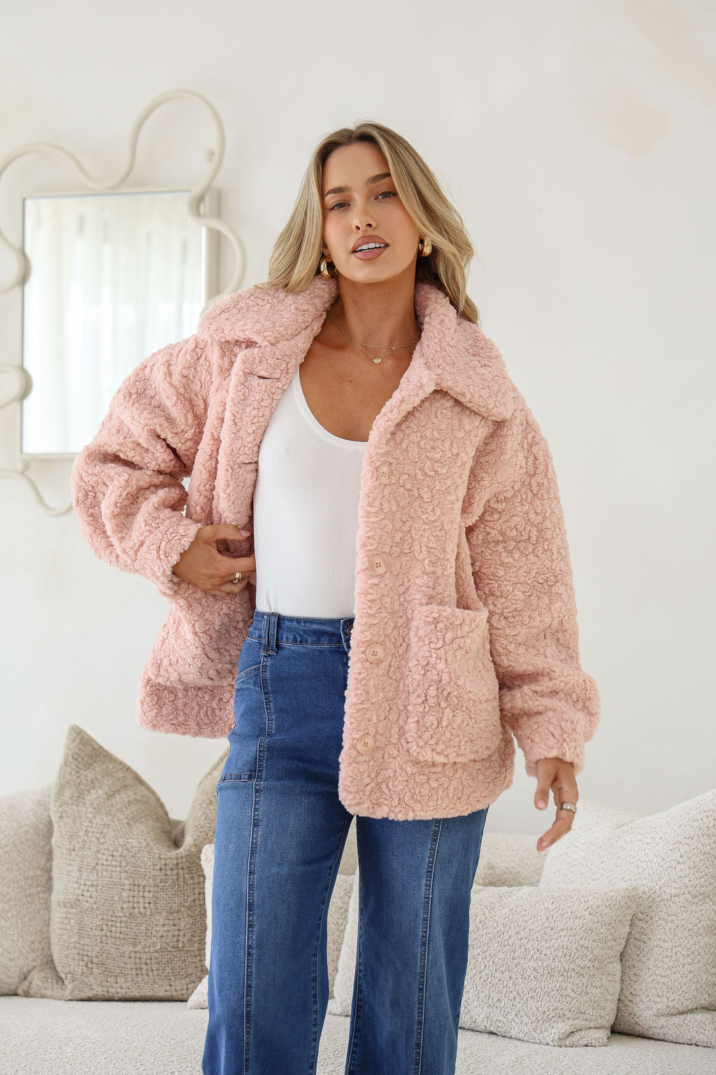 Woman wearing a pink fluffy jacket in a living room setting