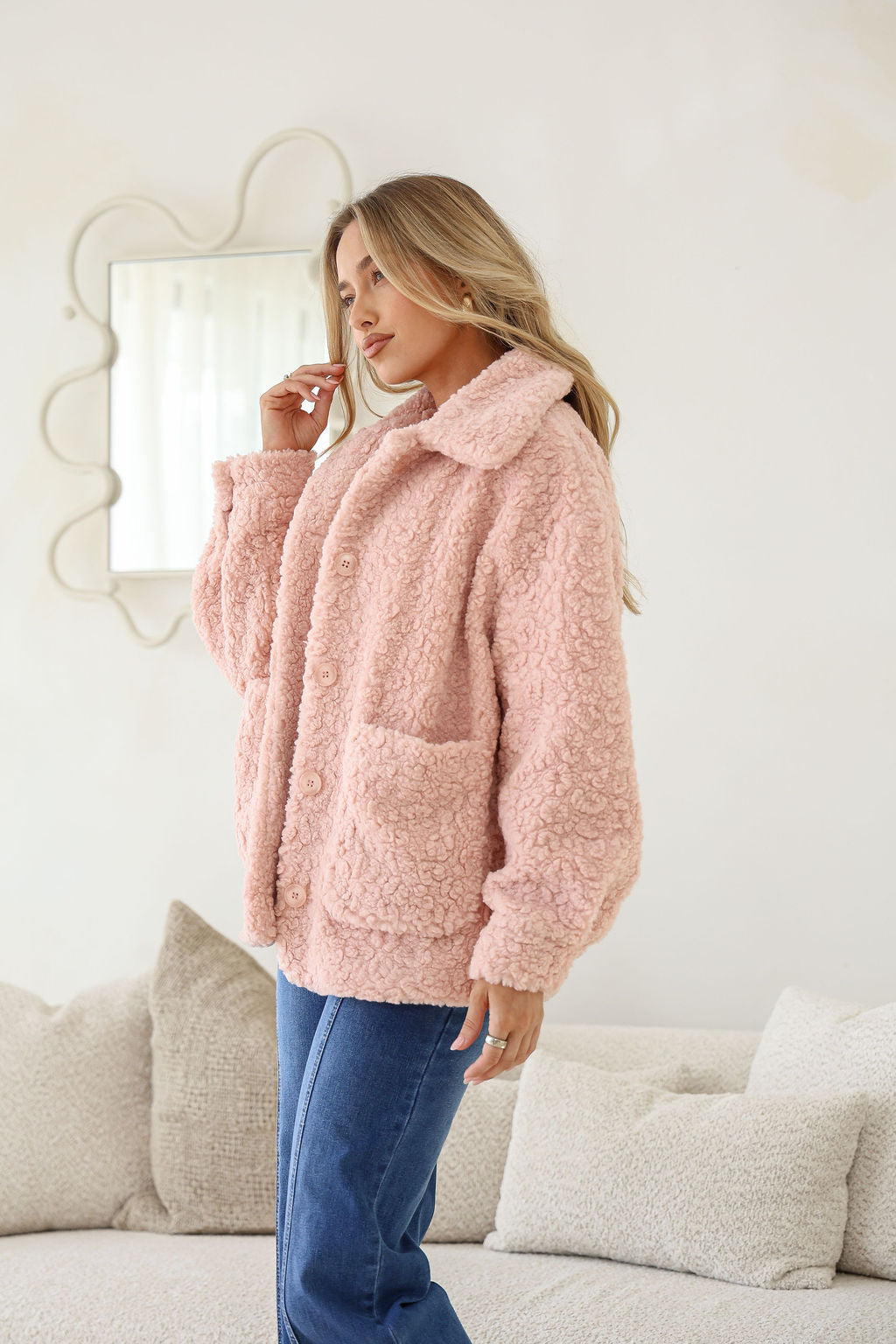 Woman wearing a pink fluffy jacket in a living room setting