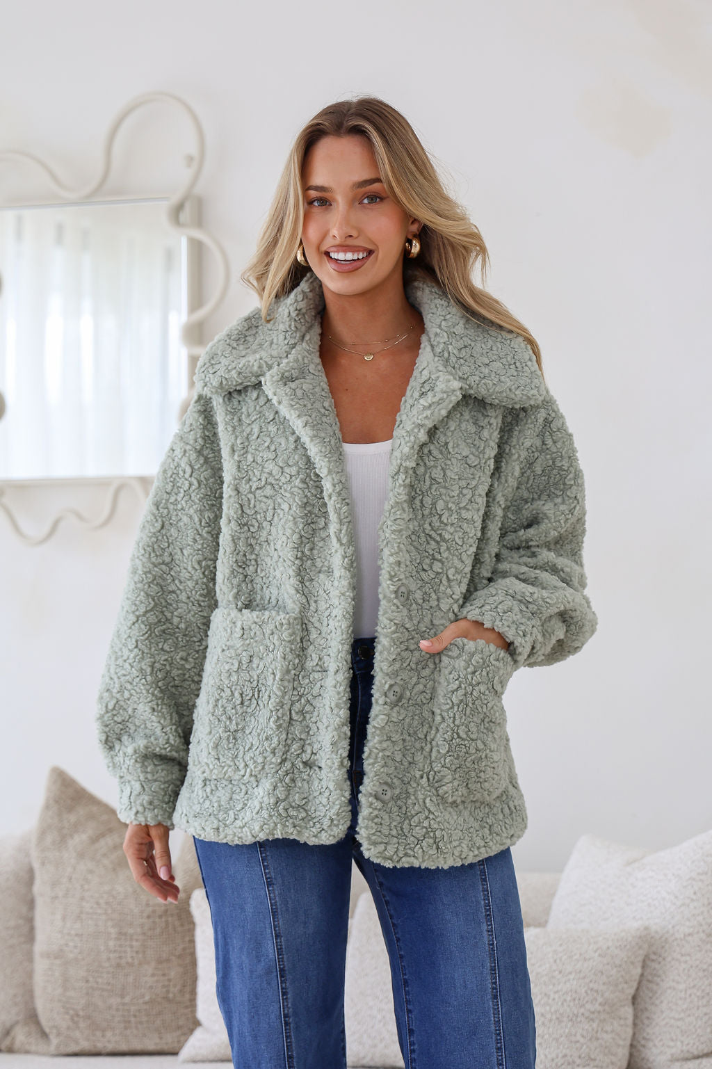 Woman wearing a green sherpa coat in a cozy living room setting