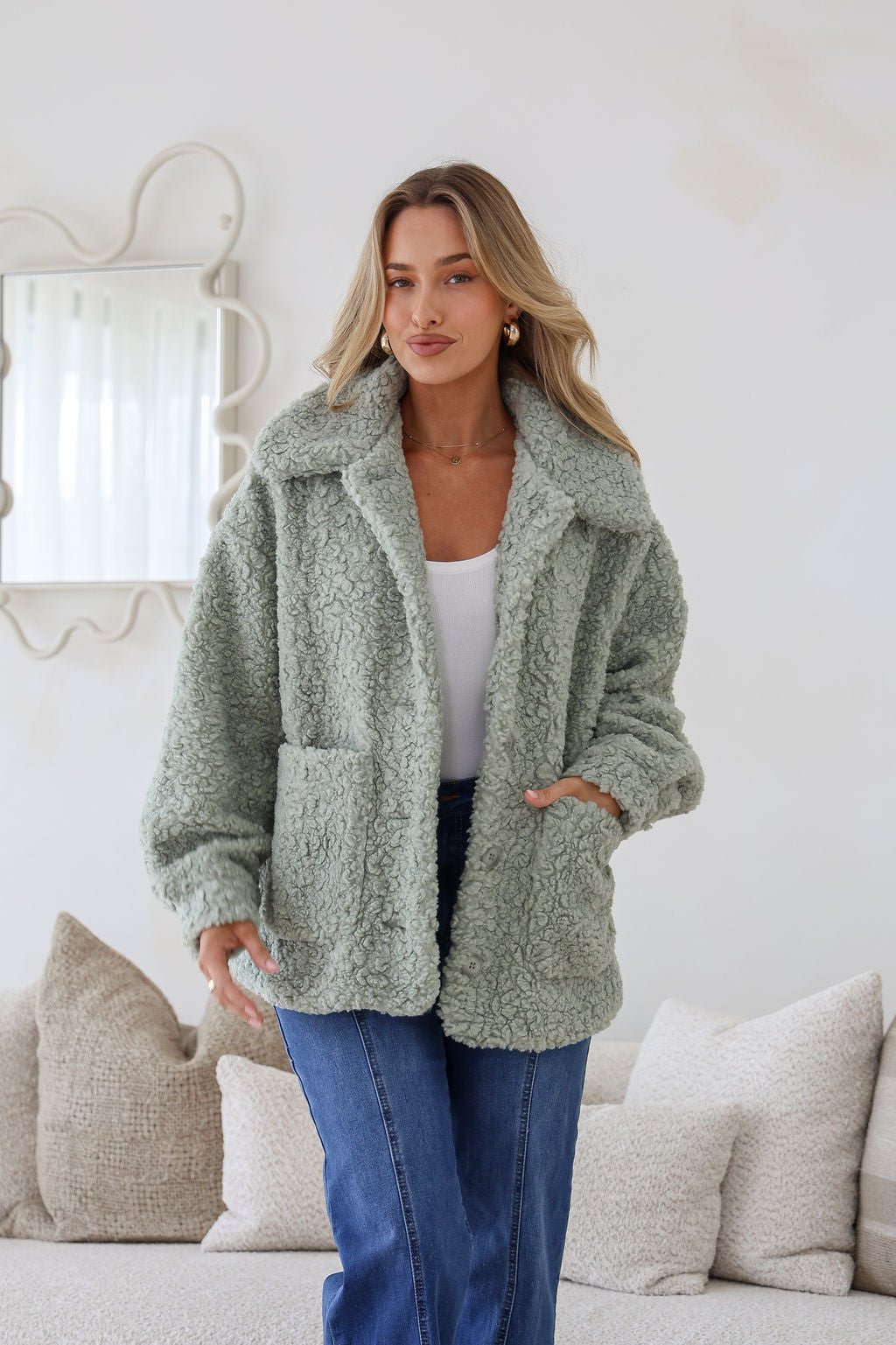 Woman wearing a green sherpa jacket in a cozy living room setting