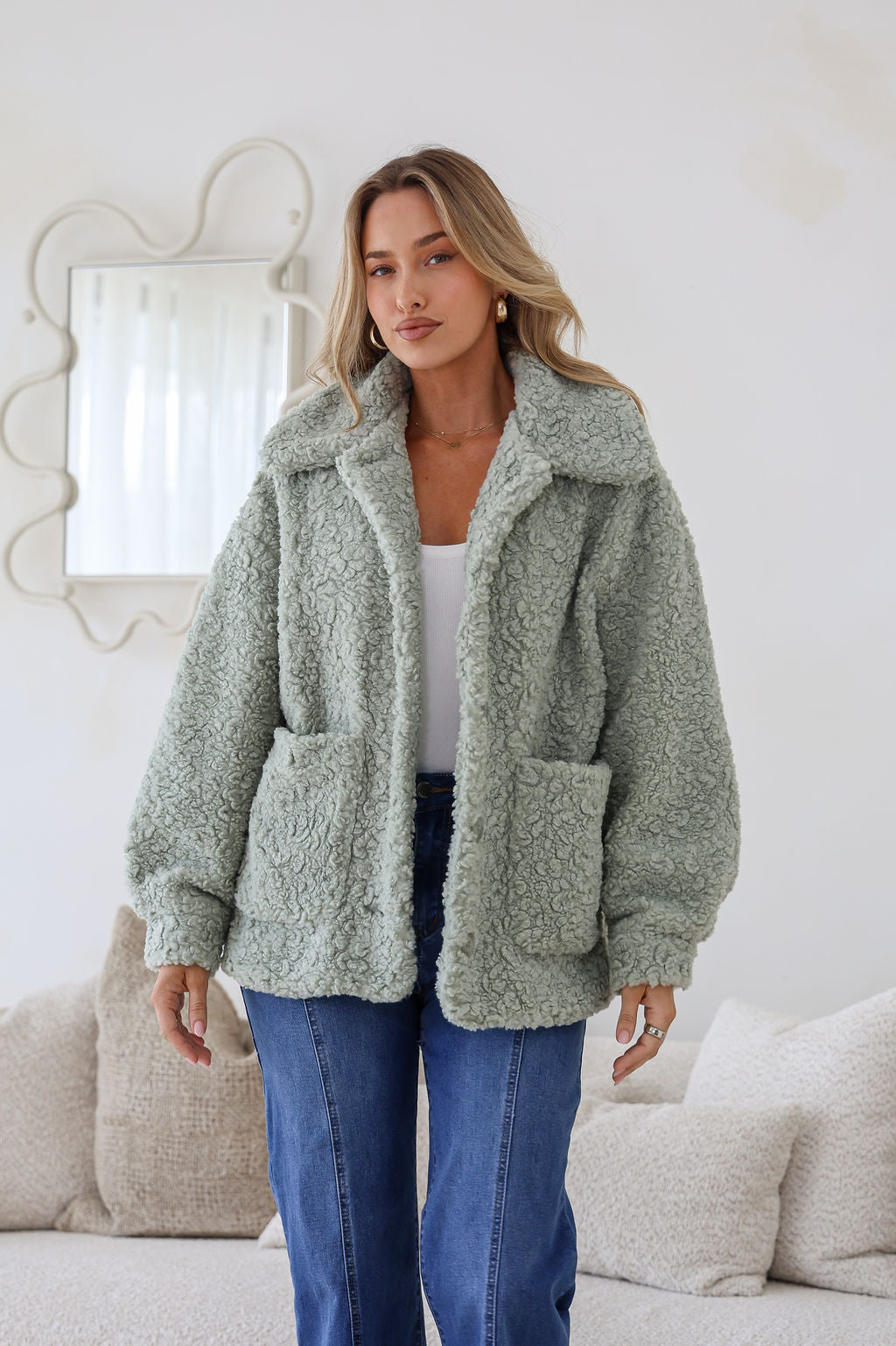 Woman wearing a green sherpa jacket in a cozy living room setting