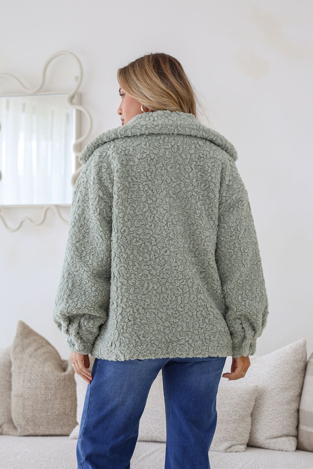 Person wearing a green textured coat in a living room setting