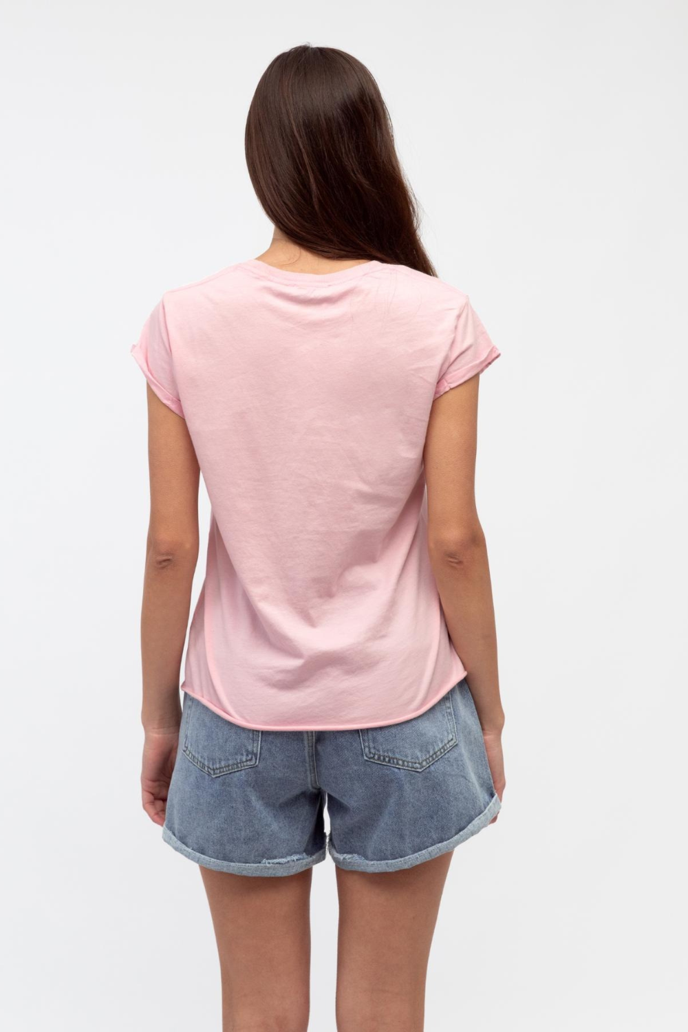 Person wearing a pink t-shirt and denim shorts on a white background