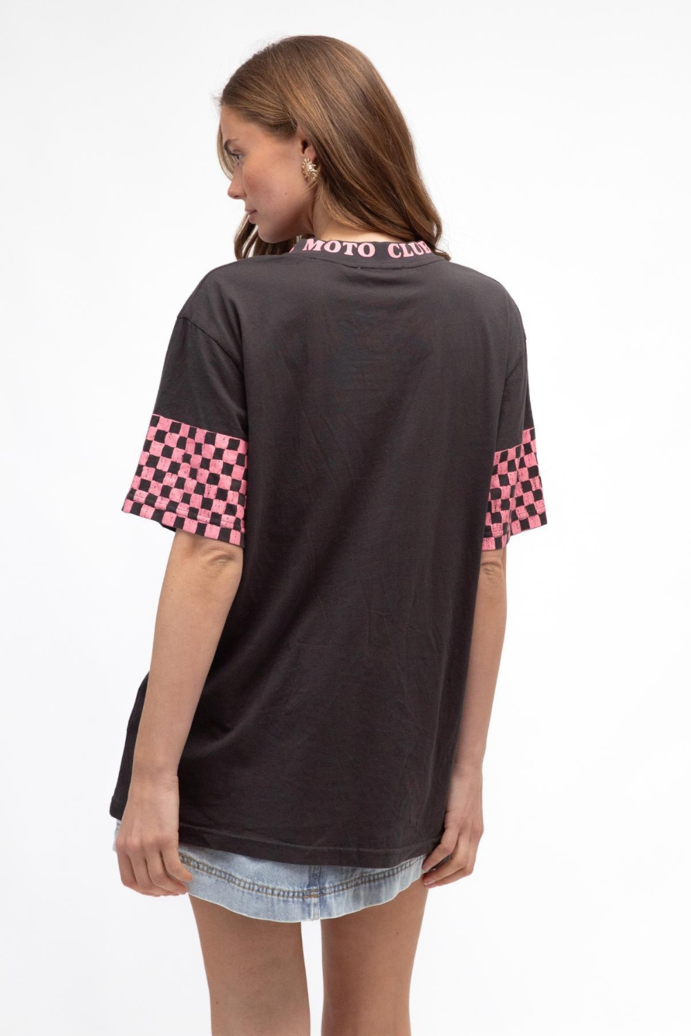 Woman wearing a black t-shirt with pink checkered sleeves on a white background