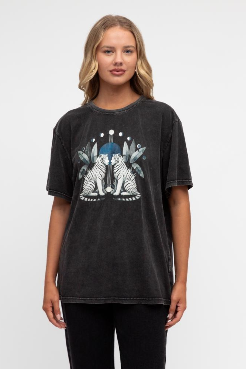 A woman wearing a vintage washed black t-shirt with a graphic of a mirrored tiger design and moon phases.