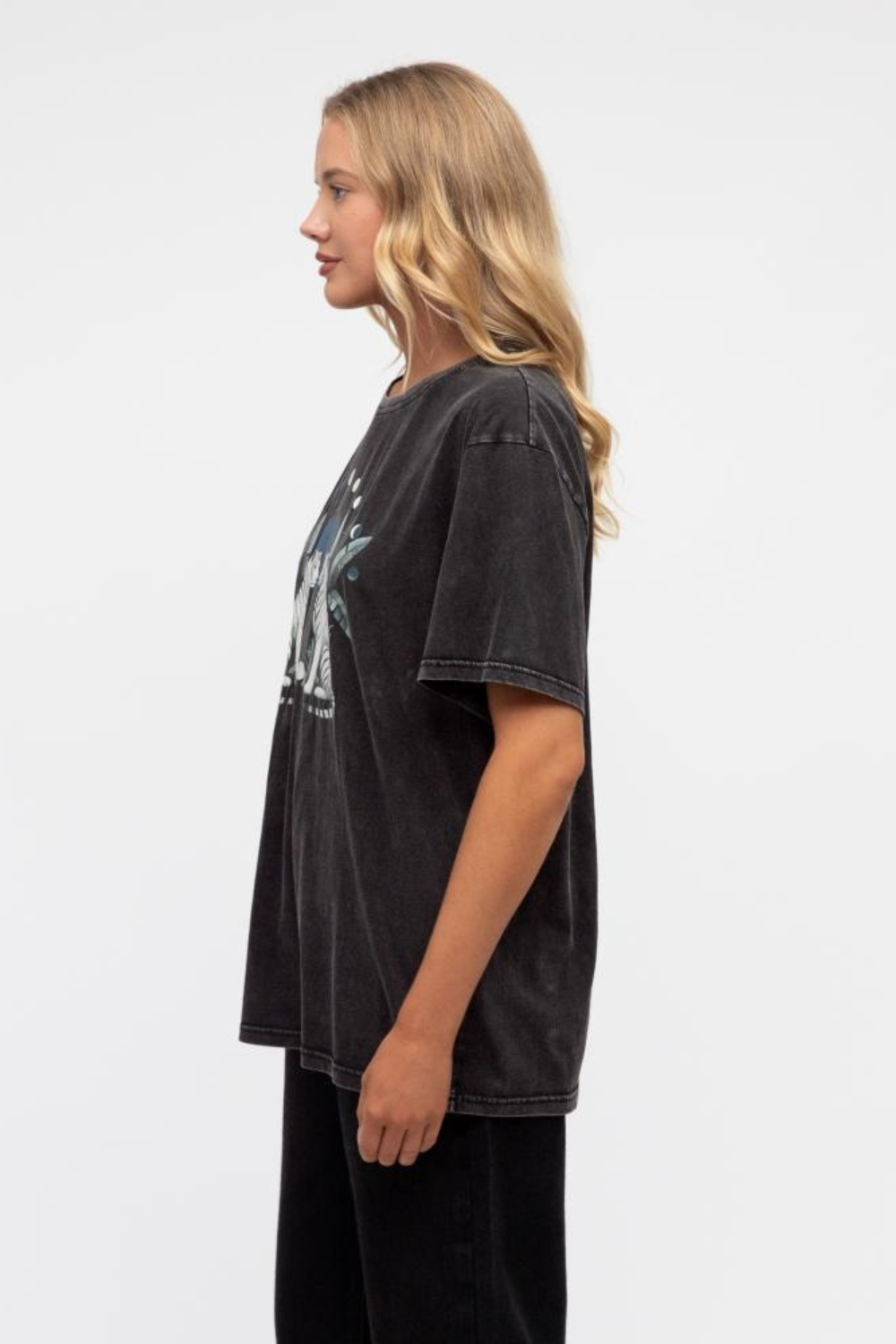 Woman wearing a black oversized t-shirt with a graphic design on a white background